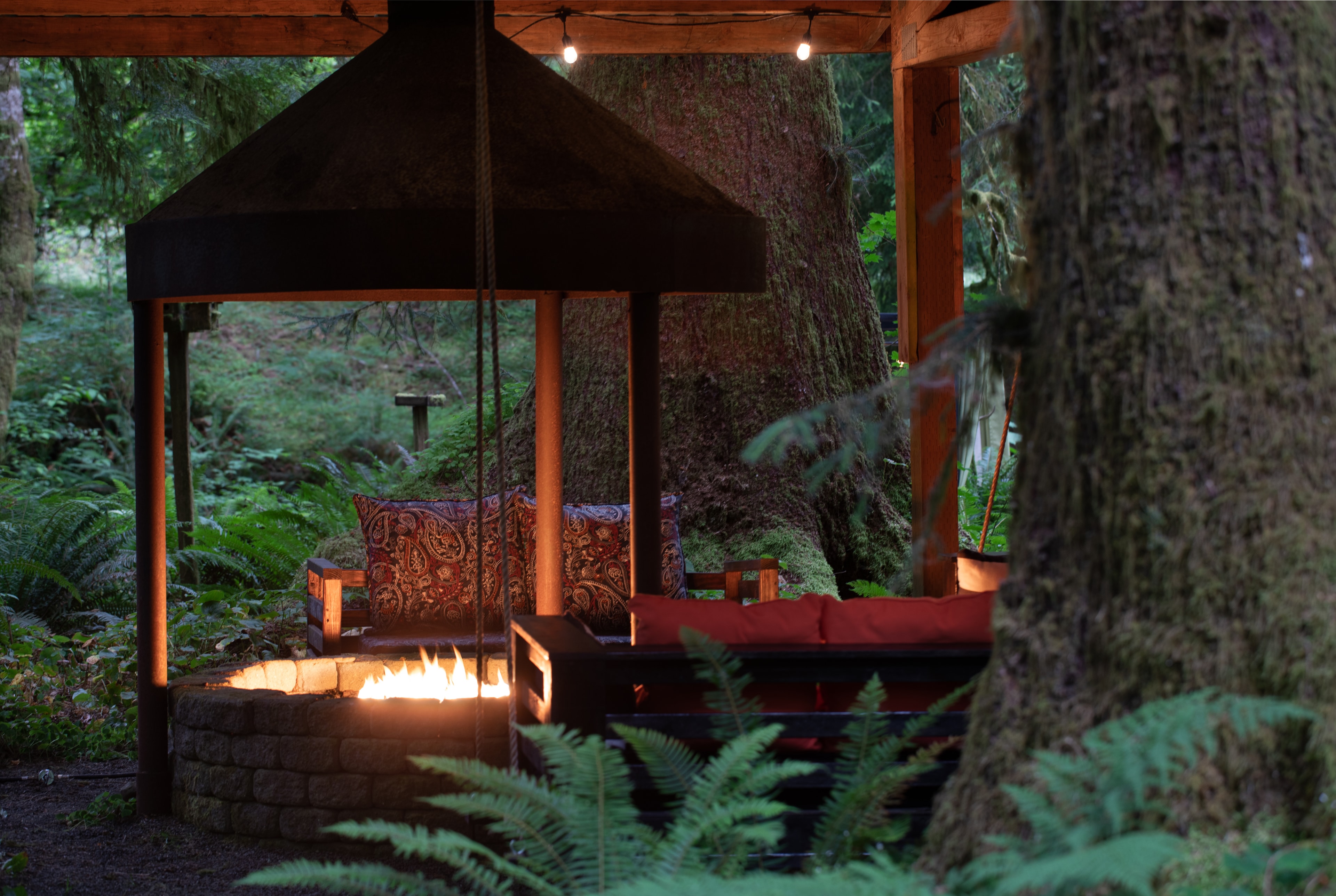 Glowing fire pit pavilion with string lights in the rainforest